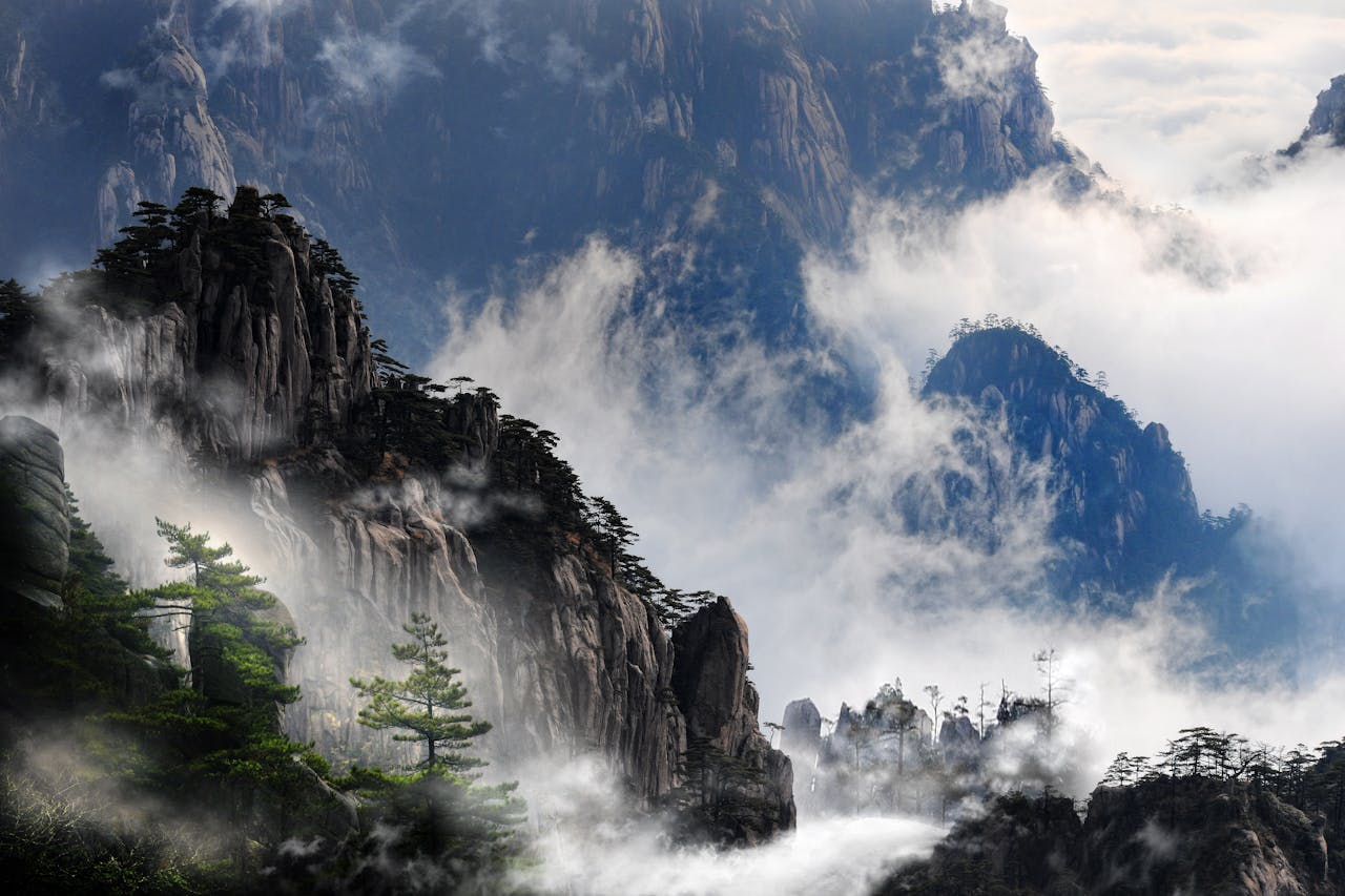 gallery-3 Misty mountain peaks of Huangshan, China enveloped in fog, creating a serene and dramatic landscape.