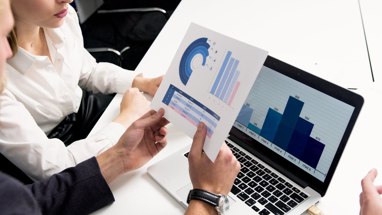 our-services-3 Business professionals discussing data charts and graphs in a modern office setting.