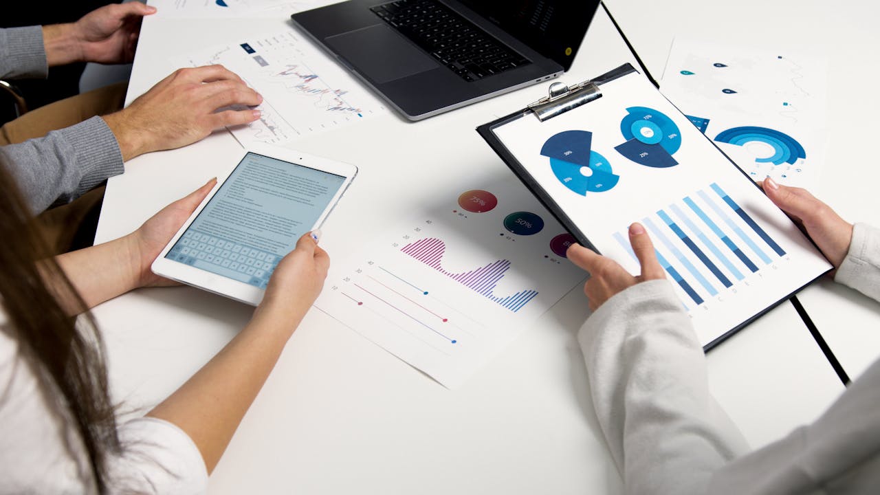 why-choose-us Team analyzing financial charts and digital reports during a business meeting.