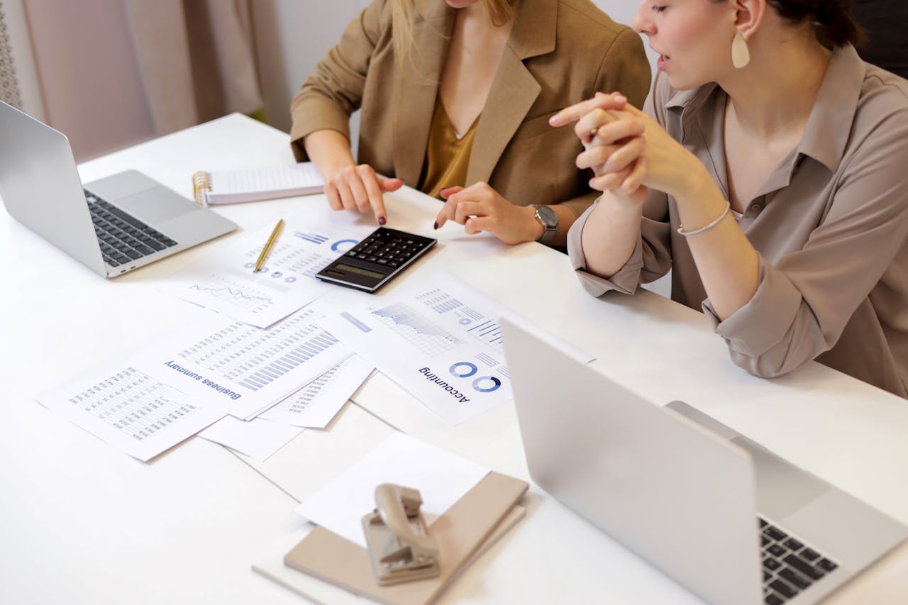 gallery-1 Two professionals collaborating on financial documents in a modern office setting.