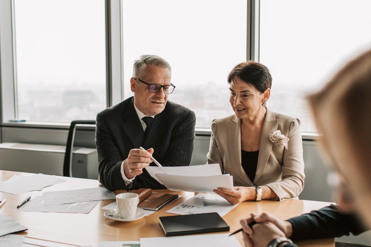 about-01 Senior business professionals discussing documents in a corporate office setting.